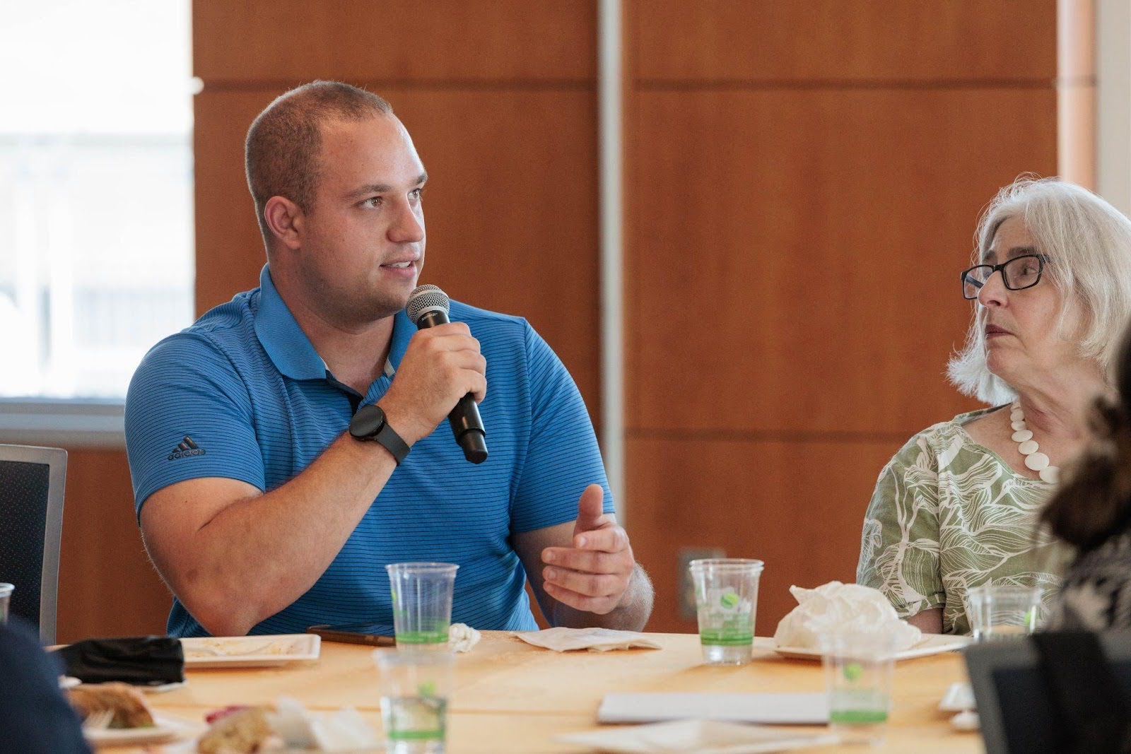 Man sitting at a table speaking into a microphone