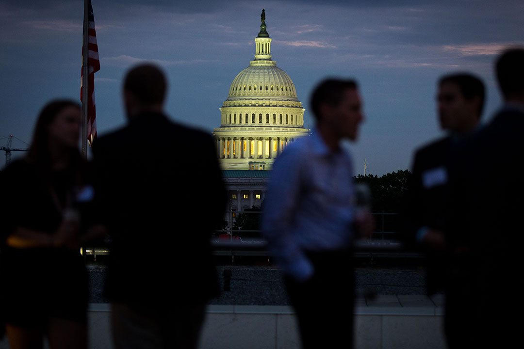 US Capitol glowing in background with shadowy networking crowd in business attire