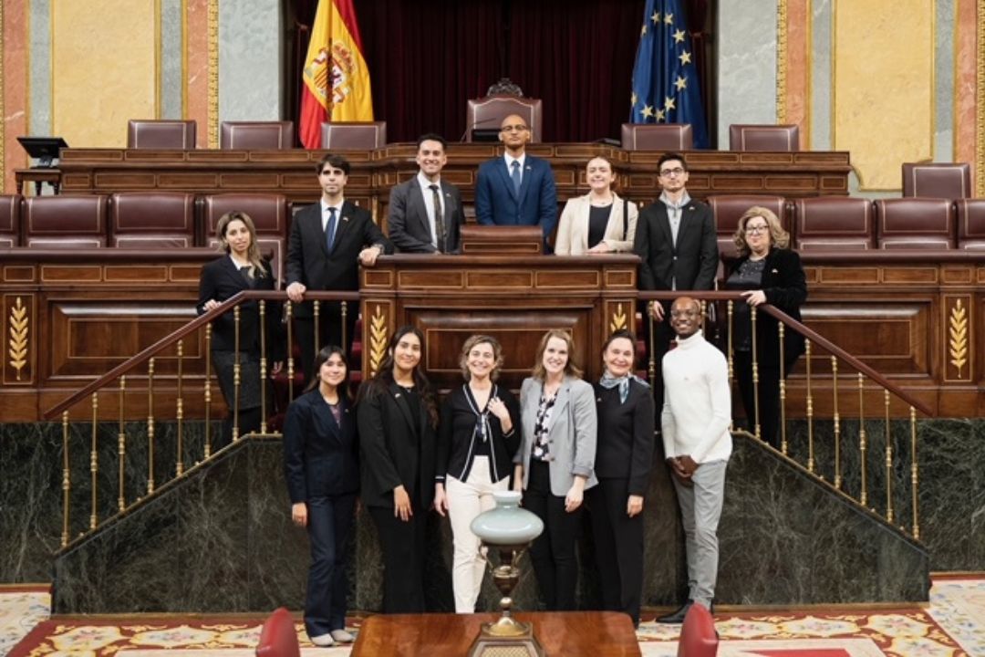Group of students and advisors smiling and posing in front of Congress of Deputies assembly seating